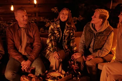 A group of colleagues sitting around a bonfire in the UK countryside, about to share a meal